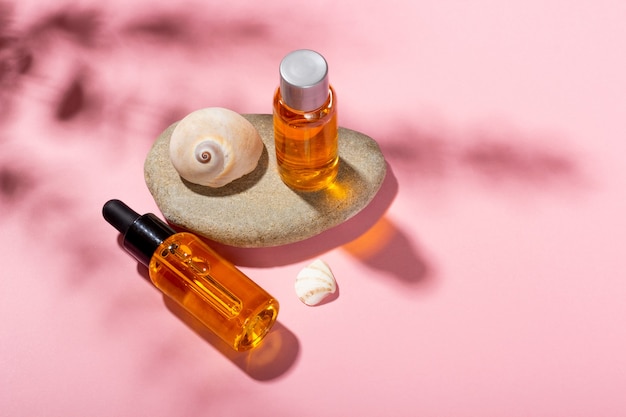 Zonnebrandolie. Cosmetische producten naast schelpen in zonnestralen op een roze achtergrond. Zonbeschermende cosmetica.