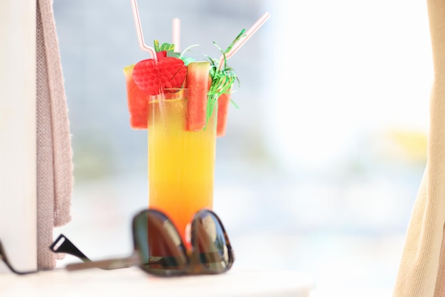Zonnebril die dichtbij alcoholisch cocktailglas liggen op strandclose-up