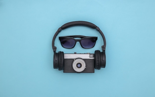 Zonnebril met stereo koptelefoon en camera op blauwe achtergrond. Plat leggen. Bovenaanzicht