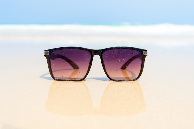 Zonnebril op wit zandstrand. Similan-eilanden, Thailand. zonnebril wordt weerspiegeld in het gouden natte zand zoals in de spiegel
