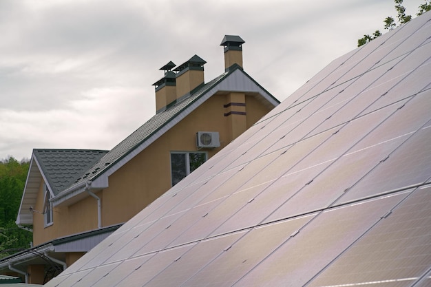 Zonnepanelen op een dak van een privéwoningGroot familiehuis uitgerust met zonnepaneel voor het verkrijgen van elektriciteitBakstenen huis met twee verdiepingen voorzien van zonne-energiebron om elektriciteit te produceren voor eigen behoeften