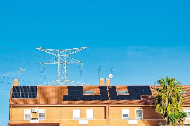 Zonnepanelen op het dak van huizen met een strakblauwe lucht op de achtergrond.