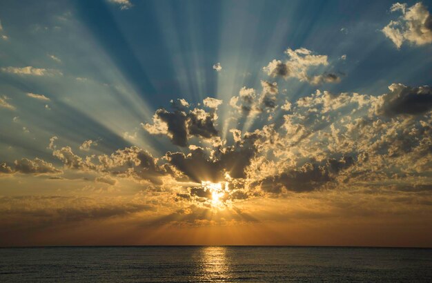 Zonnesteek met radiale zonnestralen die door wolken over de Middellandse Zee gaan