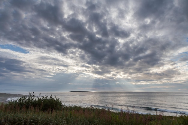 Zonnestralen die door de wolken over de zee gaan