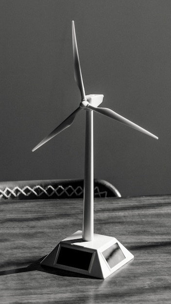 Zonnewindturbinemodel op een houten tafel in grijstinten