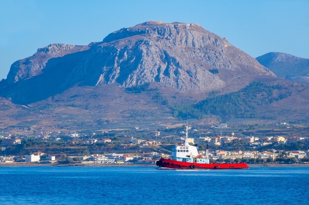 Zonnige bergachtige kust en sleepboot