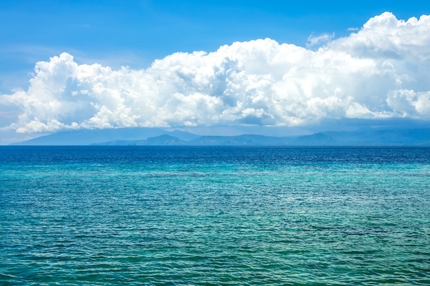 Zonnige dag in Indonesië. Turkoois water van kalme oceaan. Verrassend mooie wolken boven de verre kust