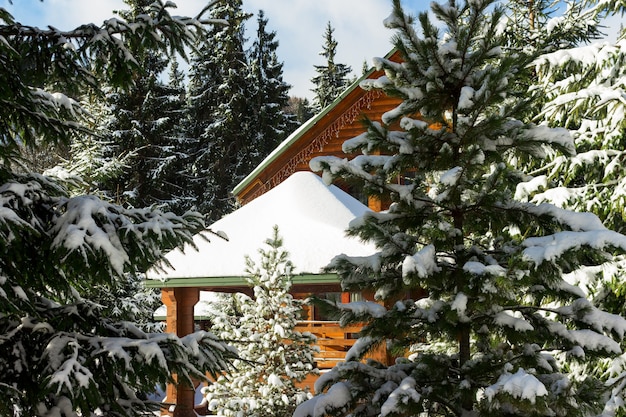 Zonnige winterdag in het bos. Houten huisje of chalet bedekt met sneeuw. Ski- en snowboardresort, wintervakanties buitenshuis.