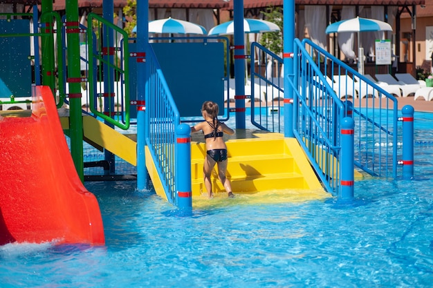 Zonnige zomerdag in het waterpark meisje geniet van vakantie en recreatie in het zwembad van entertainment c...