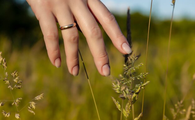 Zonnige zomerse sfeer een vrouw rijdt in het veld en gaat met haar hand over het groene gras