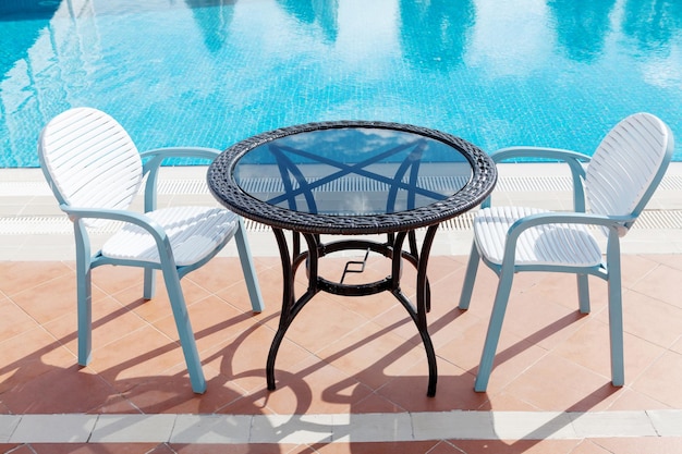 Zonnige zwembadtafel en stoelen in tropisch resort Zomervakantie concept