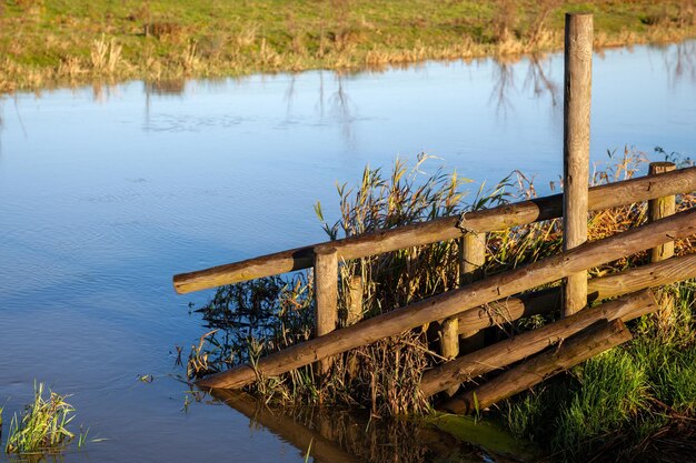 Zonovergoten houten hek bij overstroomd land bij ely