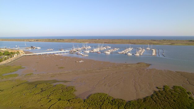 Foto zonsondergang bij de jachthaven boten in de monding van de rivier met de zee op de achtergrond luchtbeeld van de moerassen van spanje