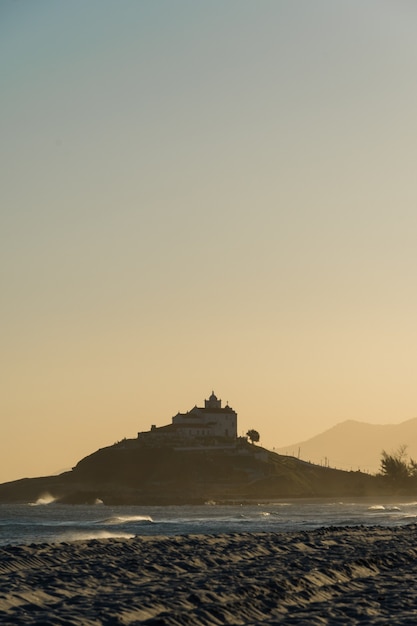 Zonsondergang bij Saquarema-strand in Rio de Janeiro, Brazilië. Beroemd om golven en surfen. Kerk op de top van de heuvel.