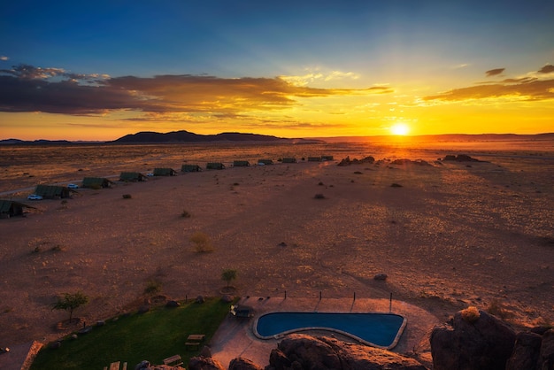 Zonsondergang boven kleine chalets van een woestijnlodge bij Sossusvlei in Namibië