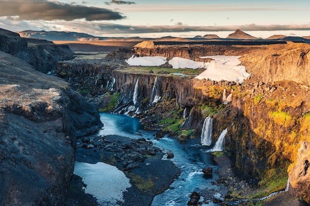 Zonsondergang boven Sigoldugljufur met een kleine waterval die in de zomer in IJsland in de canyon op de IJslandse hooglanden stroomt