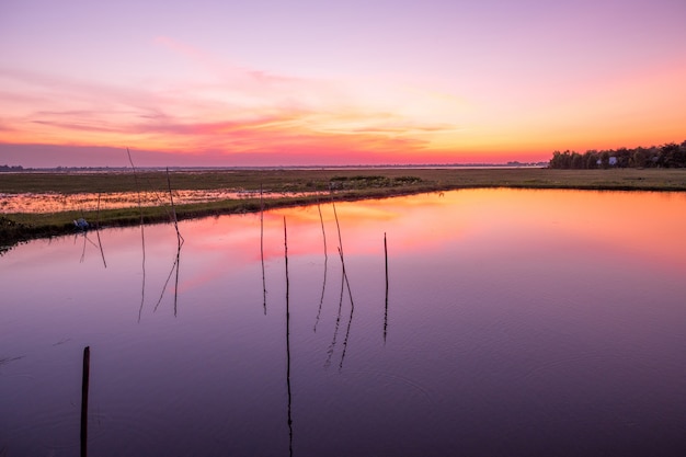 Zonsondergang die in Huay Saneng Reservor Lake, Surin, Thailand wordt weerspiegeld.