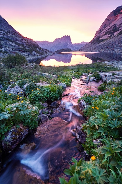 Zonsondergang in bergen dichtbij rivier. Zonlicht weerspiegeld op bergtoppen. gouden licht