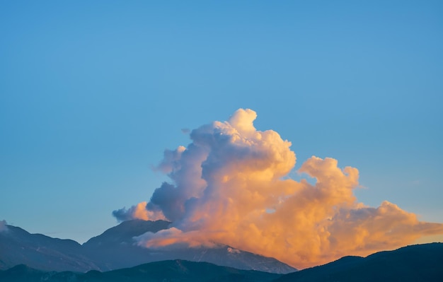 Zonsondergang in de bergen de wolken boven de berg worden verlicht door de ondergaande zon het idee voor de achtergrond het weerbehang de prachtige natuur van de bergen