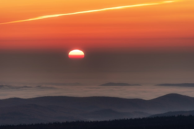 Zonsondergang in de bergen, de zon gaat onder aan de horizon.