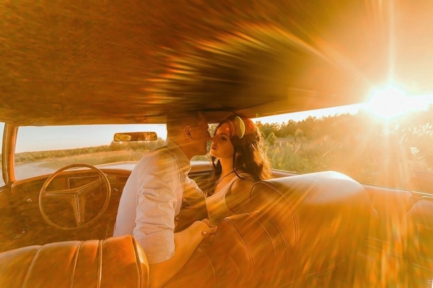 Zonsondergang liefdesverhaal vrouw en man zitten in buick riviera retro stijl met lederen interieur. Unieke zonneauto.