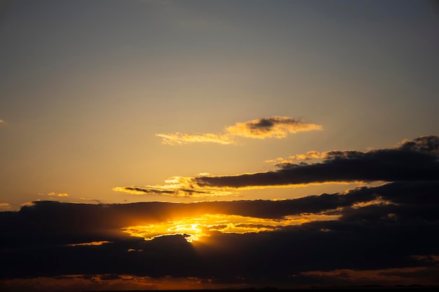 Zonsondergang of zonsopgang in een lenteveld met groen gras, wilgen en bewolkte hemel. Zonnestralen maken