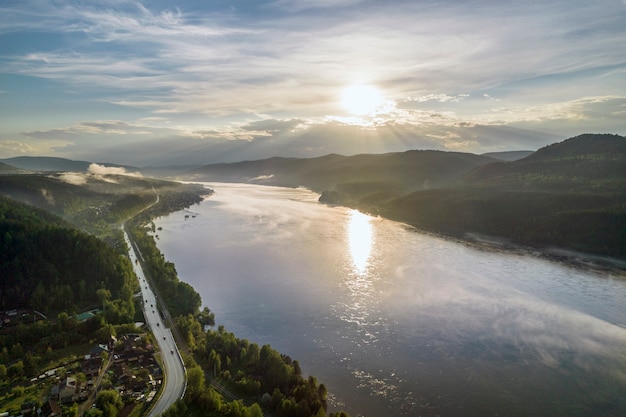 Zonsondergang op de avondzon van de rivier verlicht de heuvels en de weg langs de luchtfoto van de rivier