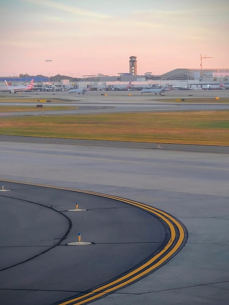 Zonsondergang op een drukke luchthaven met taxiway en vliegtuigen op de grond