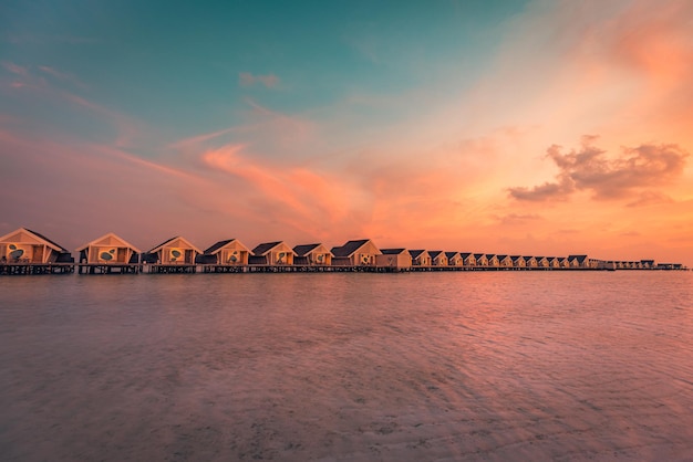 Zonsondergang op het eiland Malediven, luxe watervilla's resort en houten pier. Prachtige lucht en wolken