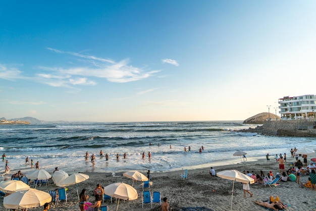 Zonsondergang op het strand met blauwe lucht en zee en witte wolken. Rots steiger. Punta Hermosa, Lima.