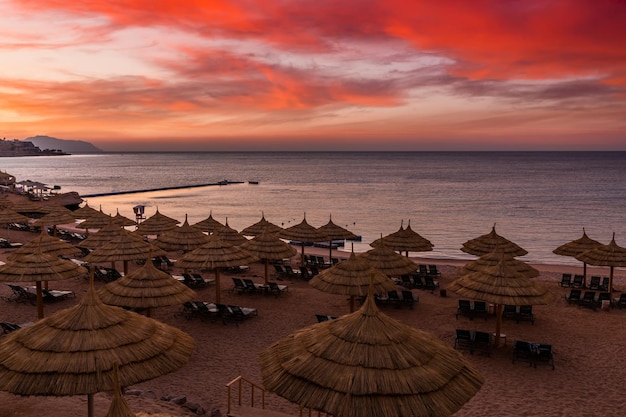 Zonsondergang op het strand met palmbomen parasols en ligbedden familievakanties aan zee rode zee egypte