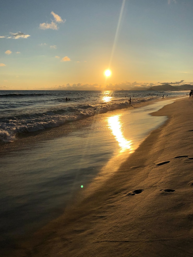 Foto zonsondergang op het strand van barra da tijuca in rio de janeiro, brazilië. zee met kalme golven.