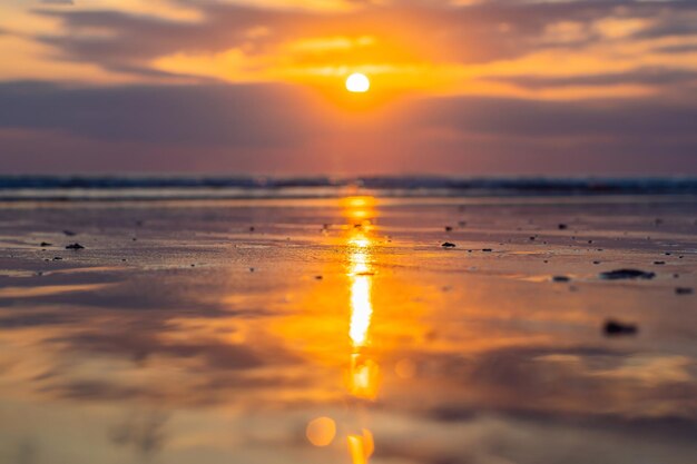 Zonsondergang op het strand van Kuta met weerspiegeling in het water op het eiland Bali