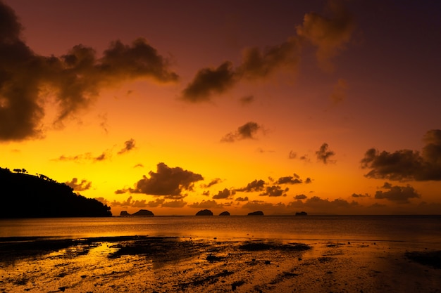 Zonsondergang op het tropische strand. Oranje zonsondergang op de Oceaan. Kleurrijke zonsondergang in de tropen