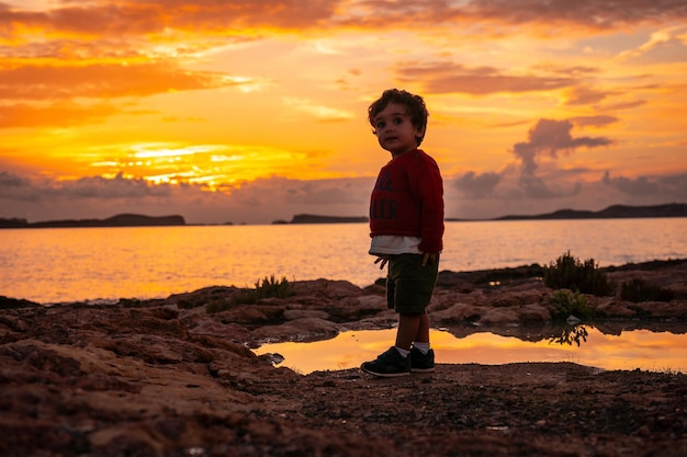 Zonsondergang op Ibiza op vakantie een eenjarige jongen die plezier heeft aan zee in San Antonio Abad