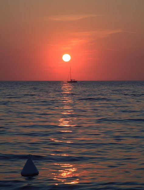 Zonsondergang op zee met een zeilboot