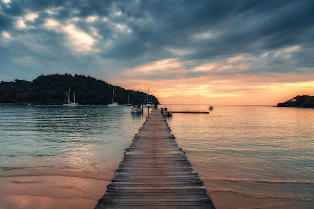 Zonsondergang over houten pier en boot in tropische zee op Koh Kood Island