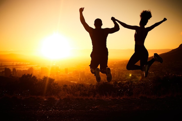 Zonsondergang silhouet paar springen en een natuurwandeling avontuur voor het winnen van fitness oefening leuke vakantie en uitzicht op de stad Zomer cardio buitentraining en training motivatie voor succes van de gezondheid van het lichaam