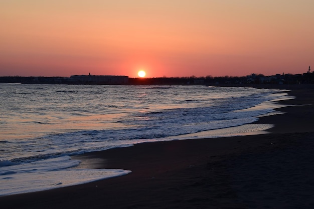 Zonsondergang zeelandschap Warme maart-dag kalme zee zacht zand en houten uitkijktoren