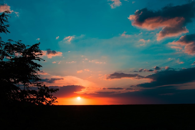 Zonsondergang zonsopgang boven veld of weide. Heldere dramatische hemel en donkere grond. Plattelandslandschap onder schilderachtige kleurrijke hemel bij zonsondergang zonsopgang zonsopgang.