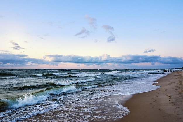 Zonsonderganghemel boven zee of oceaan met zandstrand