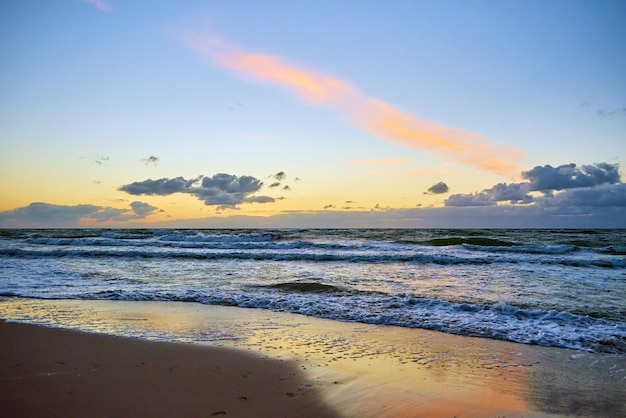 Zonsonderganghemel boven zee of oceaan met zandstrand