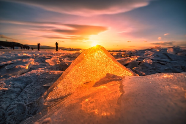 Zonsonderganghemel met natuurlijk brekend ijs over bevroren water op het Baikalmeer, Siberië, Rusland