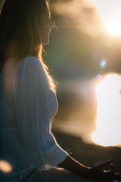 Zonsondergangmeditatie Vrouw die mediteert bij het meer bij zonsondergang