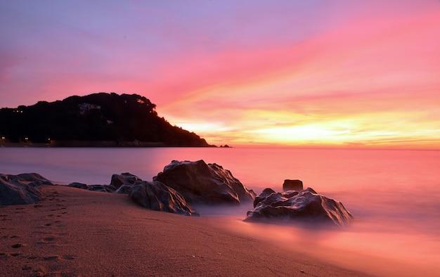 Zonsondergangstrand met rotsen