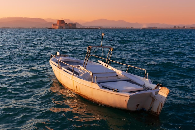 Zonsondergangzeegezicht met een boot op het water voor Mpourtzi-fort, Nafplion, Griekenland