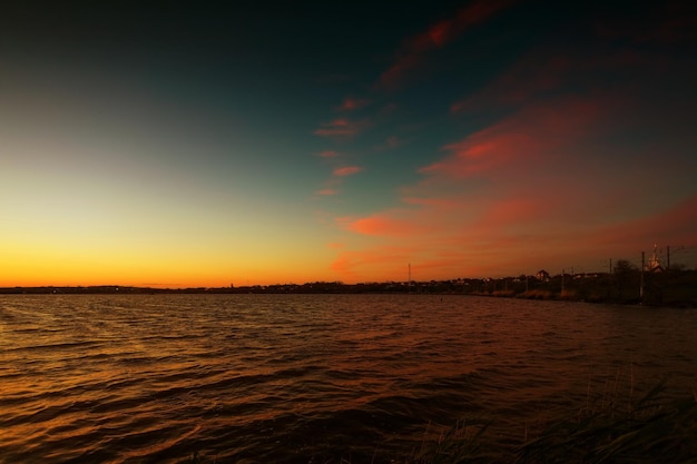 Zonsopgang aan de oever van het meer met karmozijnrode wolken