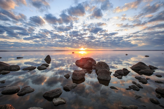 Zonsopgang boven de zee met wolken weerspiegeld in het stilstaande water