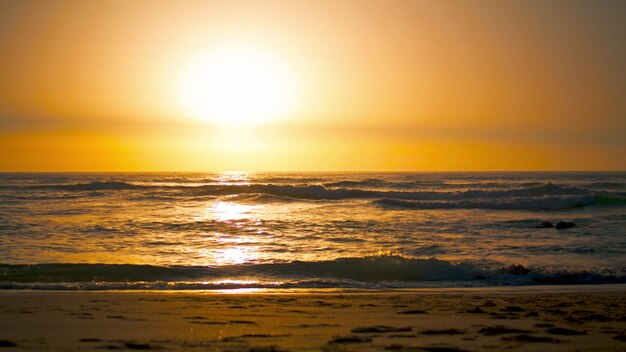 Zonsopgang landschap Ursa strand met oranje zon die de oppervlakte van de Atlantische Oceaan weerspiegelt