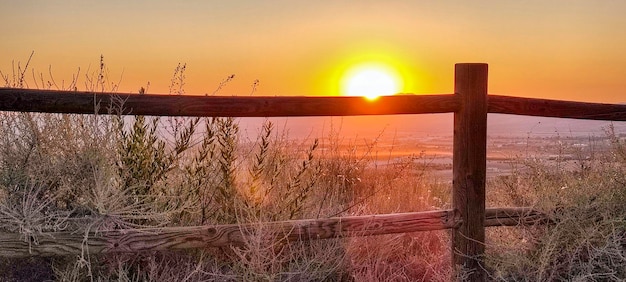 Zonsopgang met een houten hek op de voorgrond